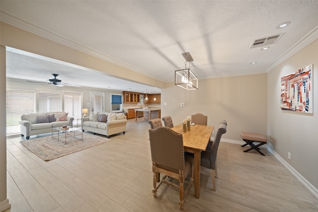 dining space featuring crown molding, ceiling fan, and a textured ceiling