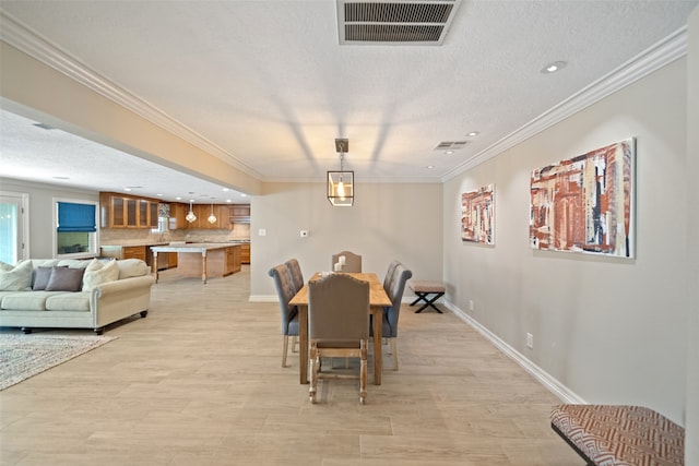 dining room featuring ornamental molding, a textured ceiling, and light hardwood / wood-style flooring