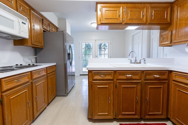 kitchen featuring white appliances, french doors, sink, light hardwood / wood-style flooring, and kitchen peninsula