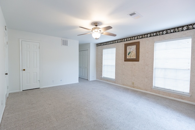 unfurnished room with light colored carpet and ceiling fan