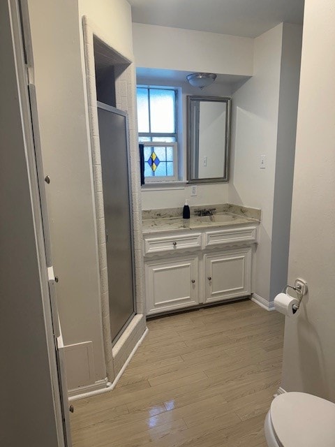 bathroom featuring hardwood / wood-style flooring, vanity, toilet, and a shower with shower door