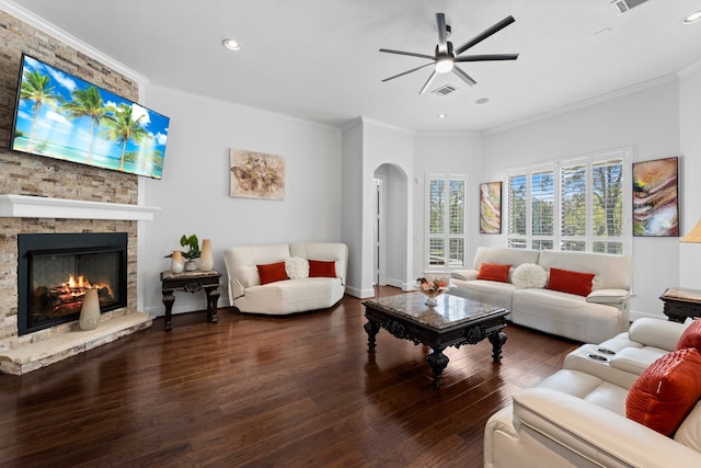 living room featuring crown molding, dark wood-type flooring, a fireplace, and ceiling fan