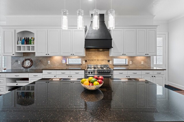 kitchen featuring white cabinetry, premium range hood, stainless steel stove, and dark stone countertops