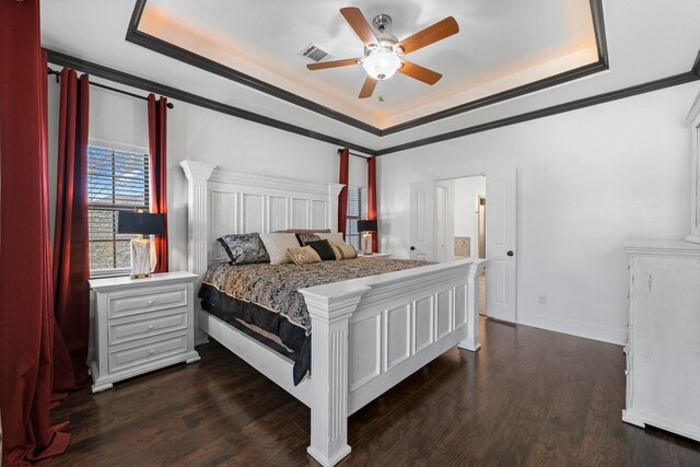 bedroom with ceiling fan, dark hardwood / wood-style flooring, a tray ceiling, and ornamental molding