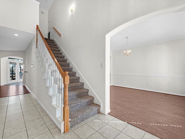 8311 Vaulted Pine Dr, Humble, TX 77346 - staircase with tile patterned floors, arched walkways, a high ceiling, a chandelier, and baseboards