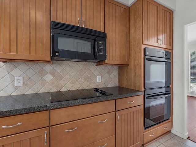 8311 Vaulted Pine Dr, Humble, TX 77346 - kitchen with black appliances, decorative backsplash, light tile patterned flooring, dark stone countertops, and brown cabinets