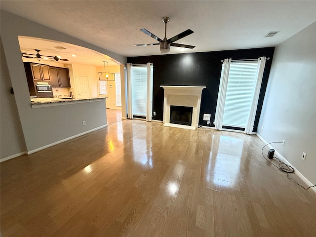 unfurnished living room featuring ceiling fan and light hardwood / wood-style flooring