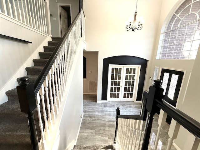 entryway with a notable chandelier, a towering ceiling, and french doors