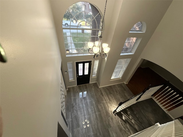 entryway with dark wood-type flooring, a high ceiling, and a notable chandelier