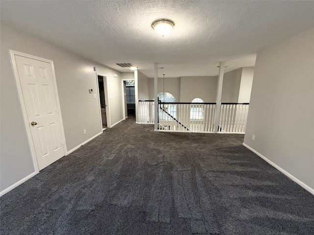 unfurnished room with dark colored carpet and a textured ceiling