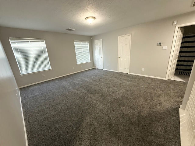 carpeted empty room with a textured ceiling