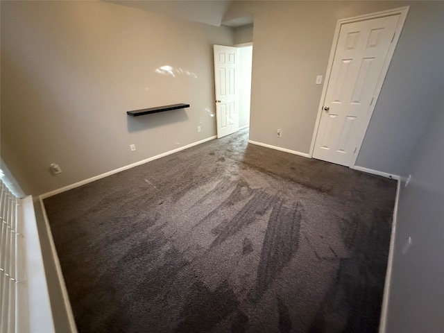 spare room featuring dark colored carpet