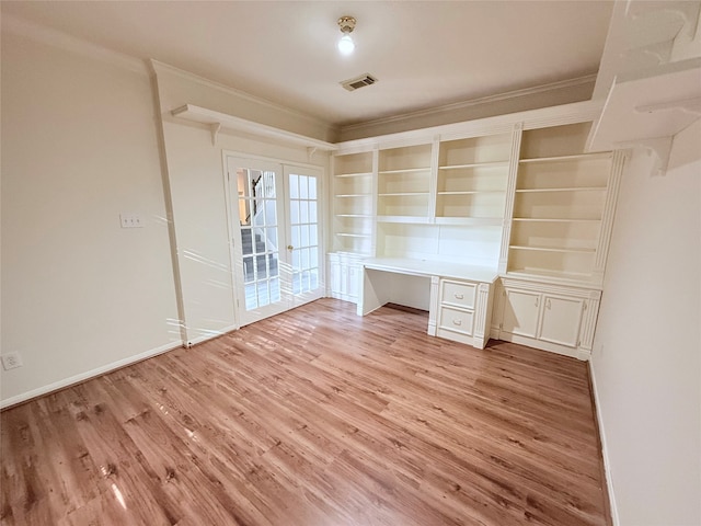 unfurnished office featuring french doors, built in desk, and light hardwood / wood-style flooring