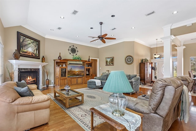 living room with ceiling fan, a fireplace, light wood-type flooring, and crown molding