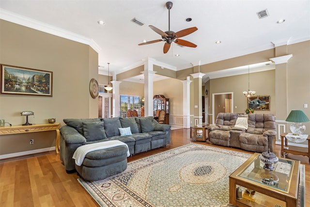 living room with decorative columns, ornamental molding, ceiling fan with notable chandelier, and light wood-type flooring