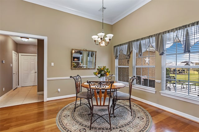 dining area with a chandelier, wood-type flooring, and ornamental molding