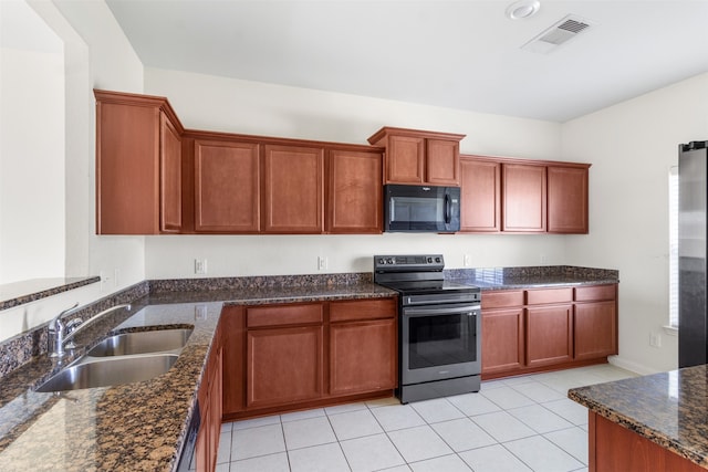 kitchen with dark stone countertops, stainless steel electric range oven, sink, and light tile patterned floors