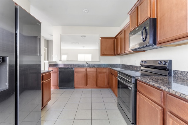 kitchen featuring light tile patterned flooring, sink, dark stone counters, and black appliances