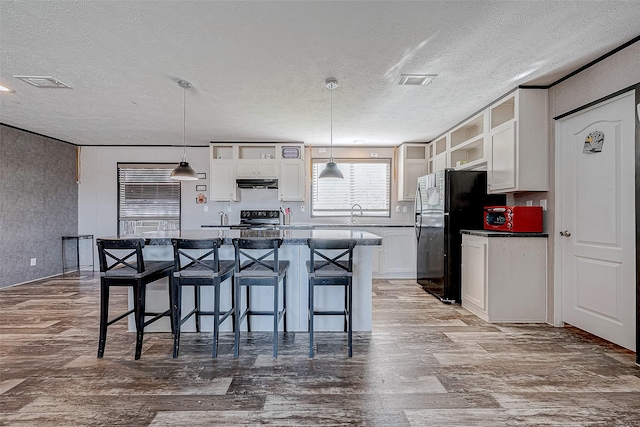 kitchen featuring a kitchen breakfast bar, white cabinetry, a kitchen island, and black appliances