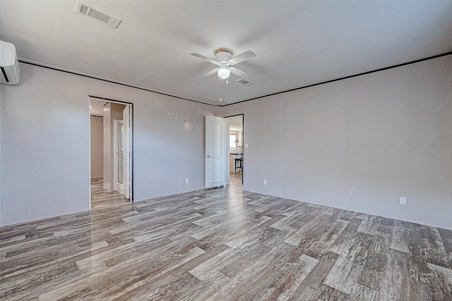 unfurnished bedroom featuring hardwood / wood-style flooring, ceiling fan, and an AC wall unit