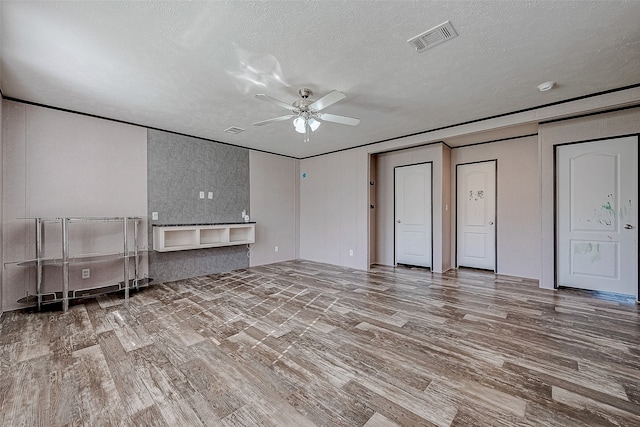 unfurnished living room featuring ceiling fan, wood-type flooring, and a textured ceiling