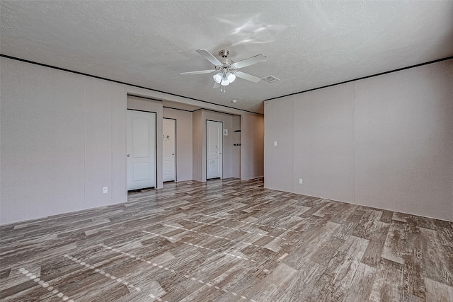 unfurnished room with ceiling fan, a textured ceiling, and light wood-type flooring