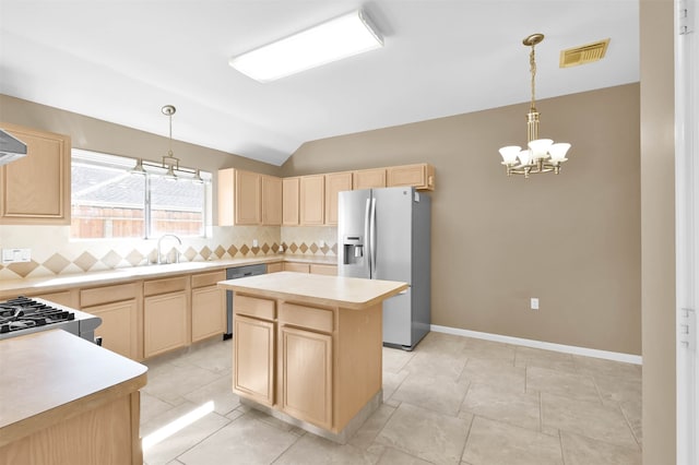 kitchen featuring light brown cabinetry, stainless steel appliances, a kitchen island, and lofted ceiling