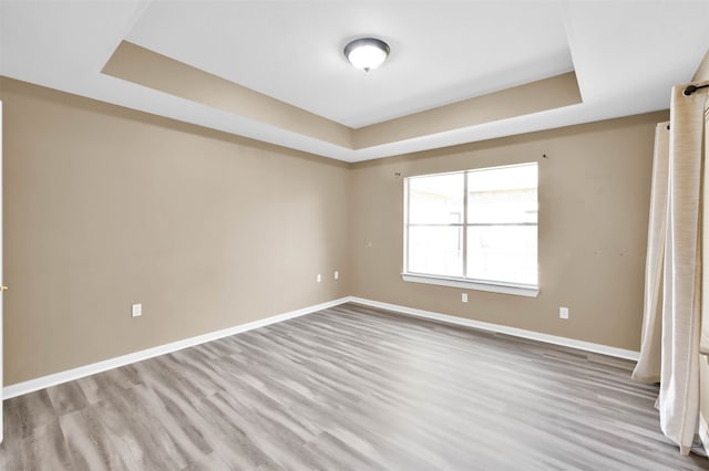 unfurnished bedroom with a raised ceiling and light hardwood / wood-style floors