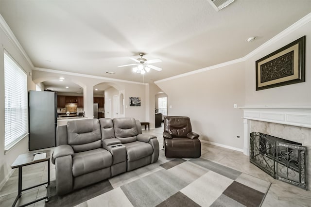 living room featuring ceiling fan, a premium fireplace, and crown molding