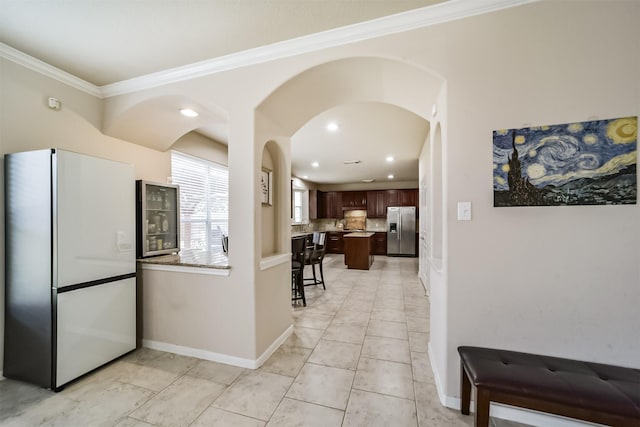 kitchen with dark brown cabinetry, stainless steel fridge, crown molding, fridge, and decorative backsplash