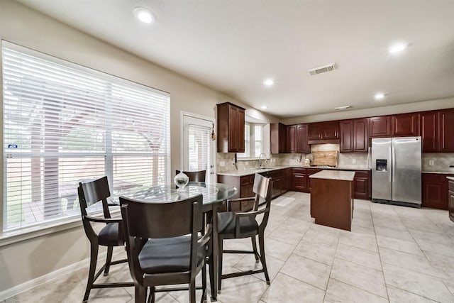 kitchen with plenty of natural light, a center island, decorative backsplash, and stainless steel appliances