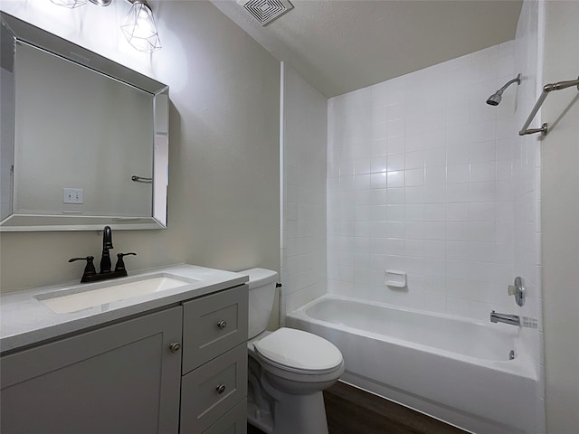 full bathroom featuring tiled shower / bath combo, a textured ceiling, toilet, vanity, and hardwood / wood-style flooring