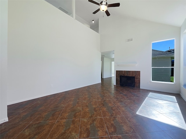 unfurnished living room with plenty of natural light, a tile fireplace, and high vaulted ceiling