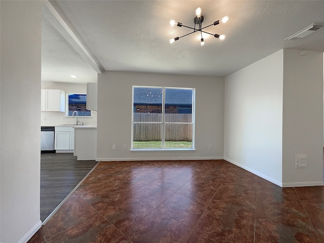 unfurnished living room featuring dark hardwood / wood-style flooring, a textured ceiling, a notable chandelier, and sink