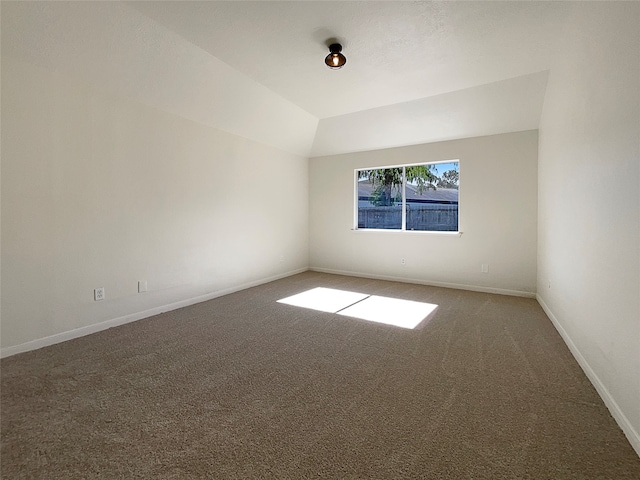 carpeted empty room with vaulted ceiling