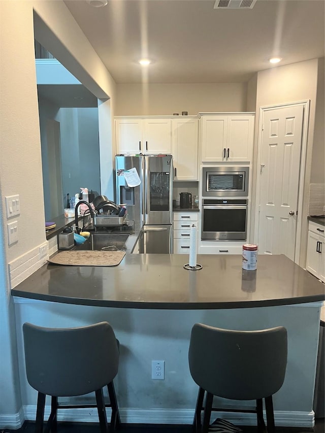 kitchen with a breakfast bar area, white cabinets, and appliances with stainless steel finishes