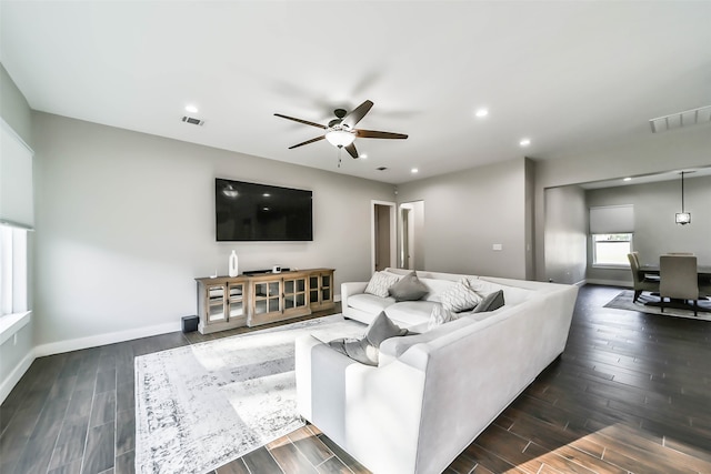 living room featuring ceiling fan and dark wood-type flooring