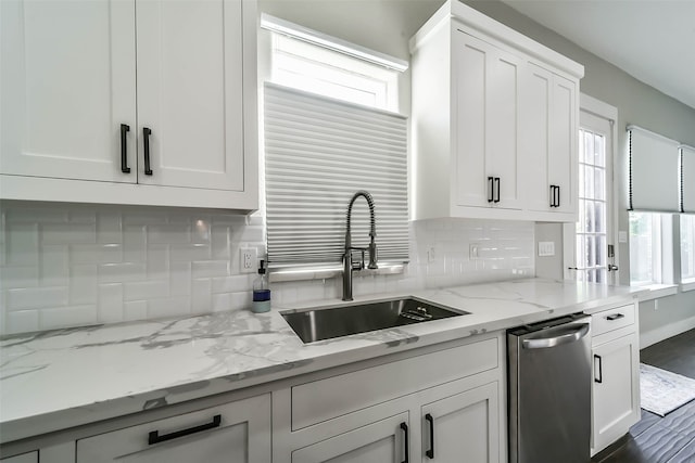 kitchen with light stone counters, dark wood-type flooring, sink, dishwasher, and white cabinets