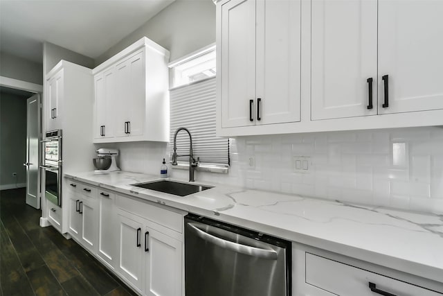 kitchen with light stone countertops, sink, stainless steel appliances, dark hardwood / wood-style floors, and white cabinets