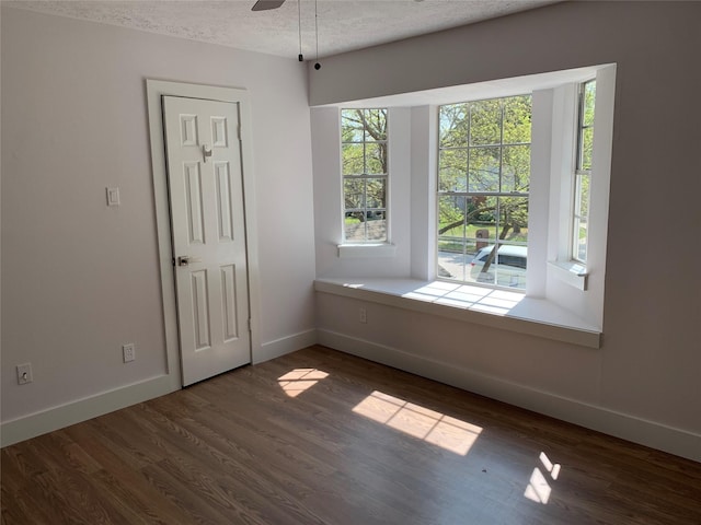 spare room with dark hardwood / wood-style flooring, ceiling fan, and a textured ceiling