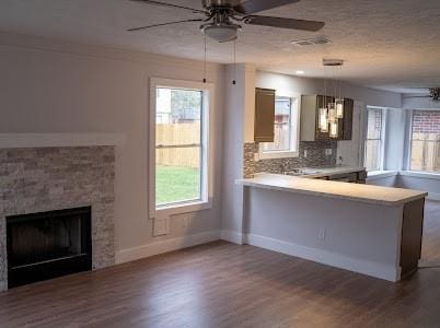 kitchen featuring hanging light fixtures, a stone fireplace, a wealth of natural light, and kitchen peninsula