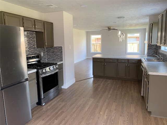 kitchen featuring decorative light fixtures, tasteful backsplash, wood-type flooring, sink, and stainless steel appliances