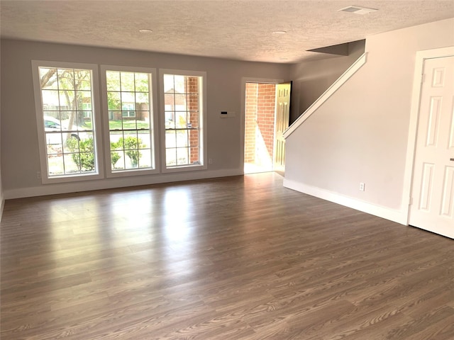 unfurnished living room with dark wood-type flooring, a wealth of natural light, and a textured ceiling