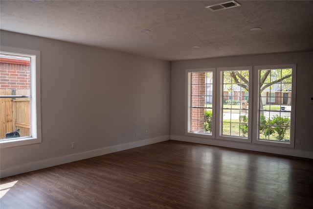 spare room featuring plenty of natural light, dark hardwood / wood-style floors, and a textured ceiling