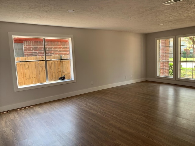 spare room featuring a textured ceiling and dark hardwood / wood-style flooring