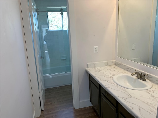 bathroom with wood-type flooring, bath / shower combo with glass door, and vanity