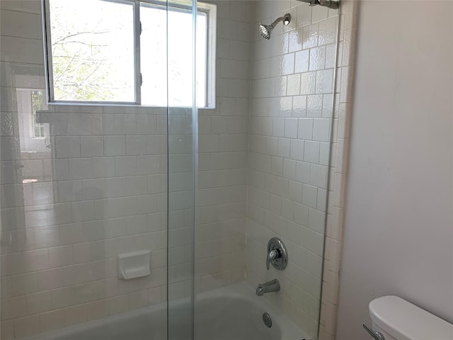 bathroom featuring tiled shower / bath combo and toilet