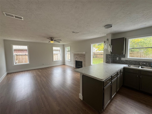 kitchen featuring a fireplace, tasteful backsplash, sink, hanging light fixtures, and ceiling fan