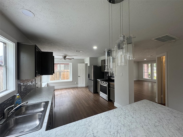 kitchen with sink, ceiling fan, appliances with stainless steel finishes, hanging light fixtures, and a textured ceiling