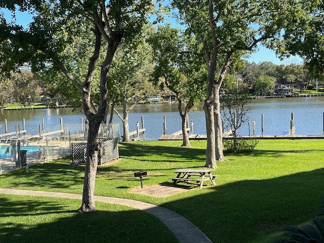 view of home's community featuring a lawn, a water view, and a dock